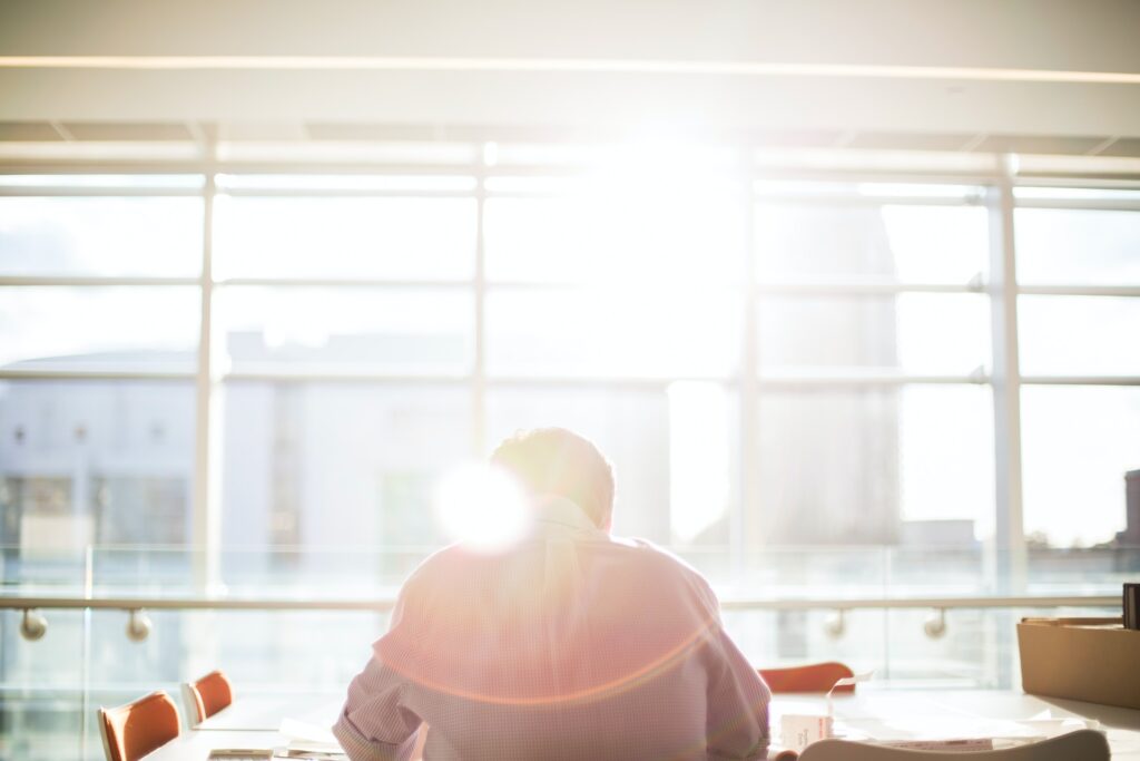 Man sitting on chair in front of window with light streaming in