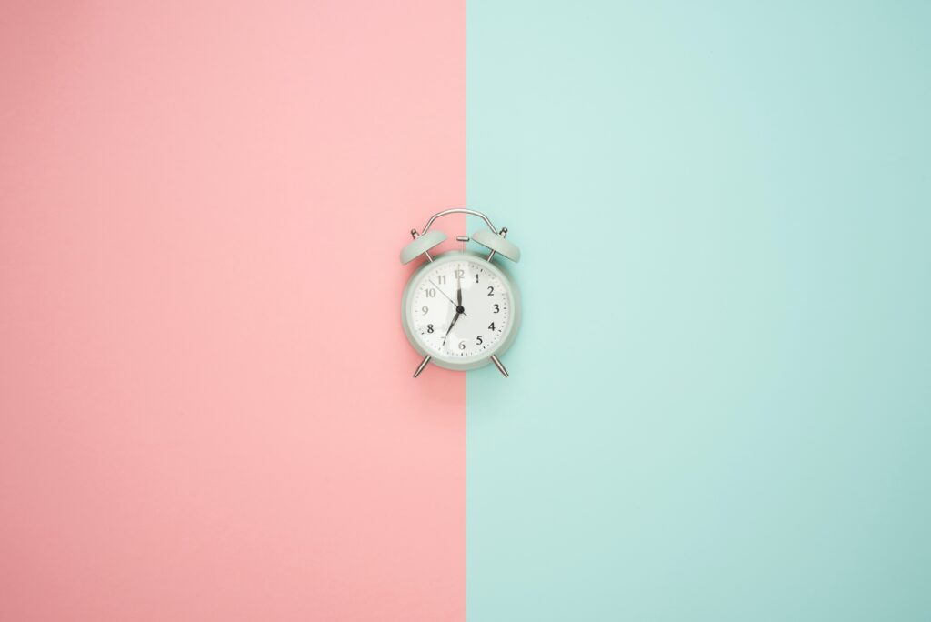 an alarm clock on a pink adn blue background
