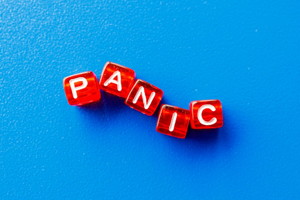 Red dice with white text spelling out "Panic" against a blue background