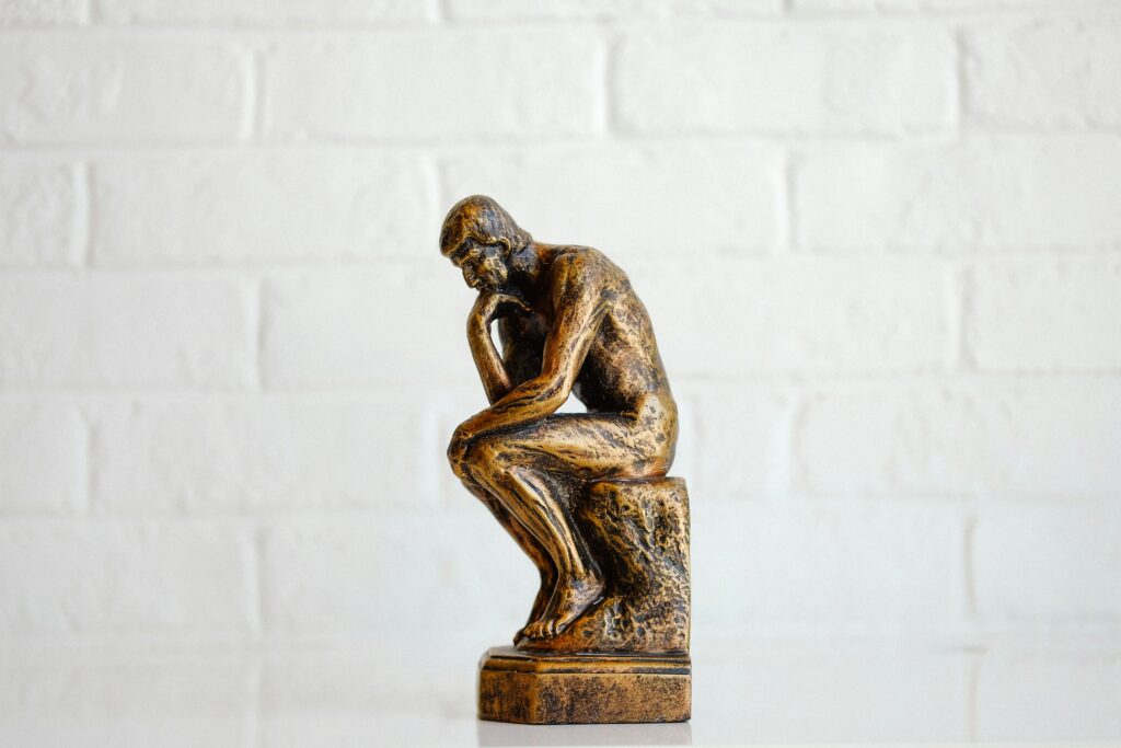 Small bronze statue of a man sitting on a rock and thinking