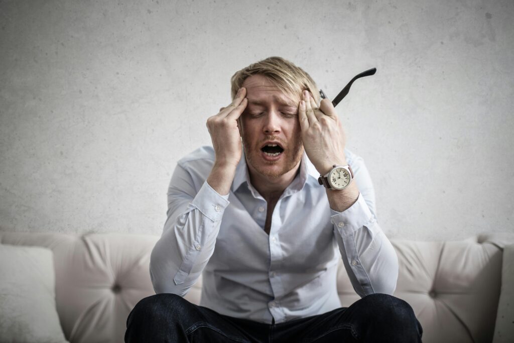 A photo of an exhausted looking man with his hands on his head