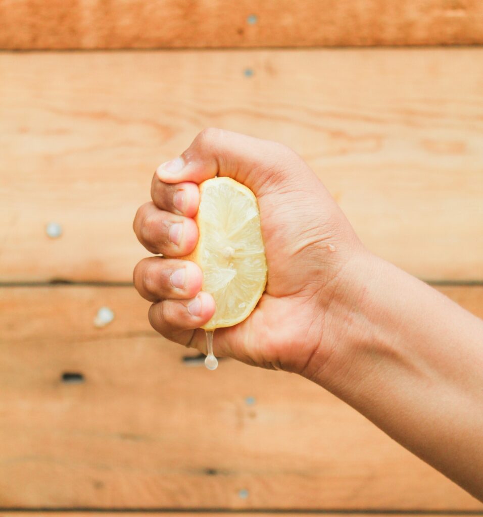 A hand squeezing half a lemon tightly