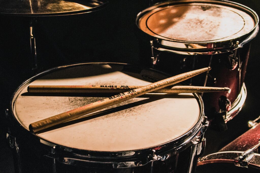 A pair of wooden drumsticks on top of a drum