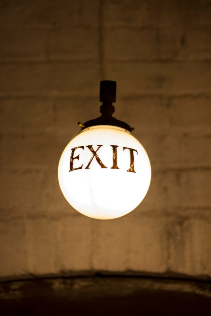 Closeup photograph of white hanging bulb light with the word exit on it