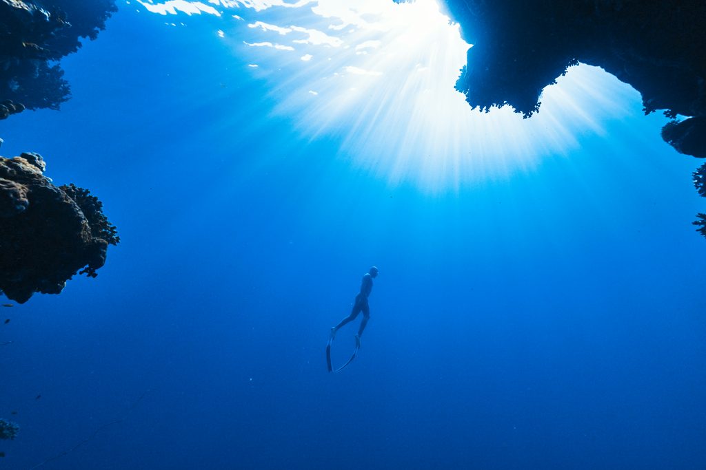 A person diving in the ocean moving towards the surface, photo by NEOM